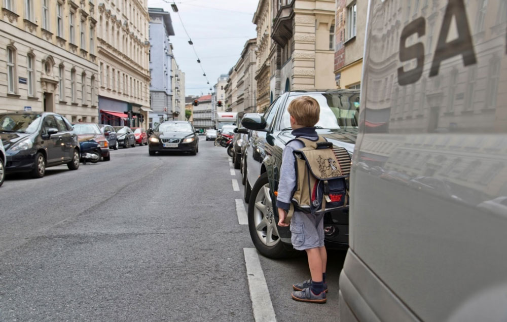Auf diesem Bild sehen Sie einen 6-jährigen Buben, der die Fahrbahn queren möchte. Glauben Sie, dass er von seiner Position aus alle verkehrsrelevanten Details wahrnehmen kann, die er als Grundlage für eine sichere Querungsentscheidung braucht? Die Antwort zeigt Ihnen das nächste Bild.