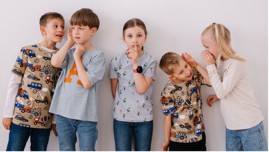 Auf dem Bild sind fünf Kinder zu sehen, die nebeneinander in einer Reihe stehen. Jedes Kind macht eine unterschiedliche Bewegung mit dem Körper oder dem Mund, um Verkehrsgeräusche nachzuahmen.