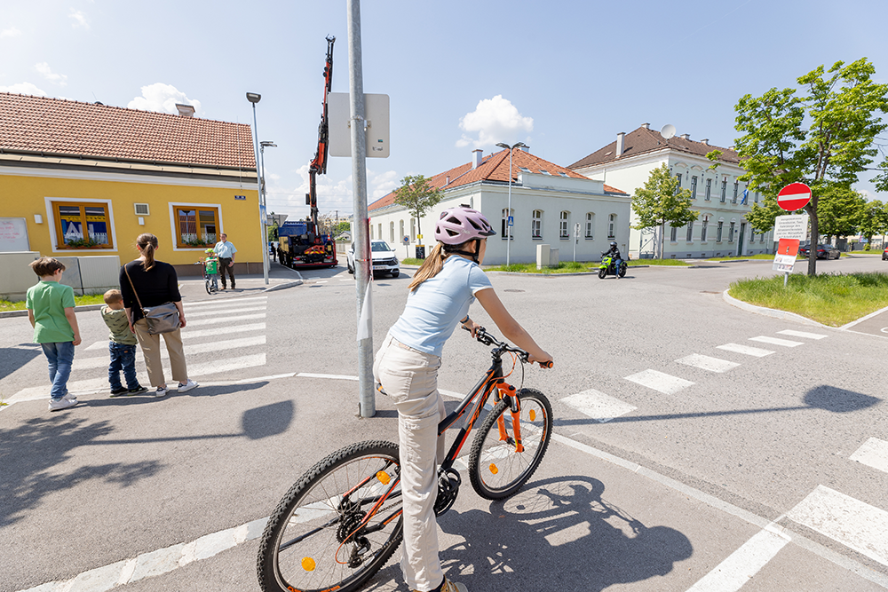 Ein Mädchen steht mit dem Fahrrad an einer ungeregelten Kreuzung.